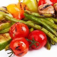 Roasted green asparagus, cherry tomatoes, and yellow vegetables on a white plate