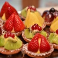 Assorted fruit tartlets topped with strawberries, kiwi, and grapes on a tray