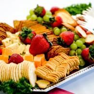 Assorted fruits and crackers arranged on a platter, including strawberries, grapes, and cheese slices.