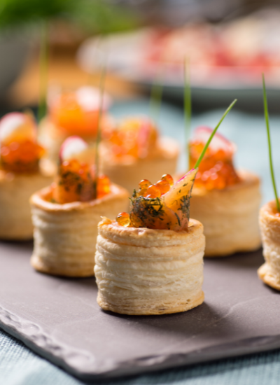 Elegant bite-sized appetizers with orange garnish arranged on a slate serving tray