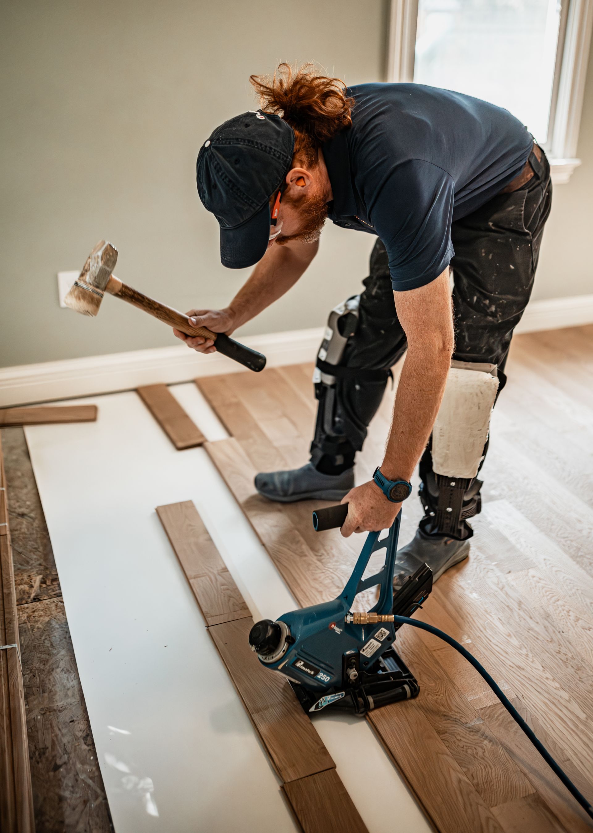 A man with a prosthetic leg is working on a wooden floor.