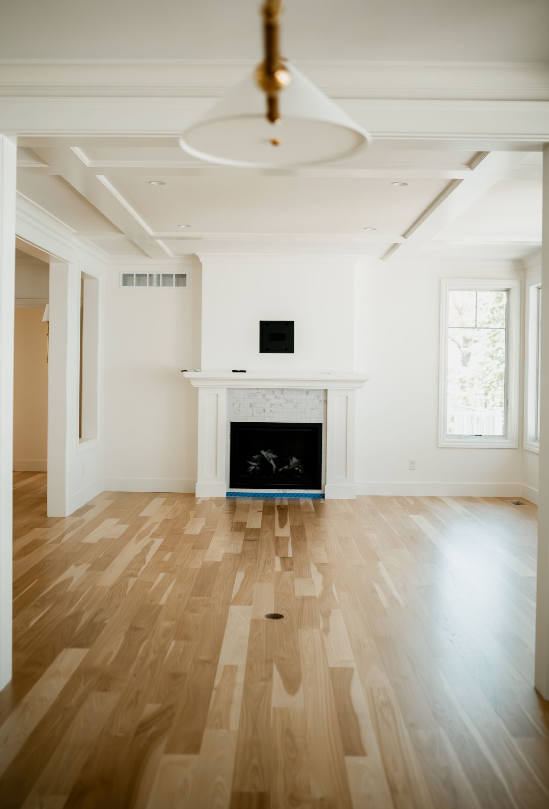 An empty living room with hardwood floors and a fireplace.