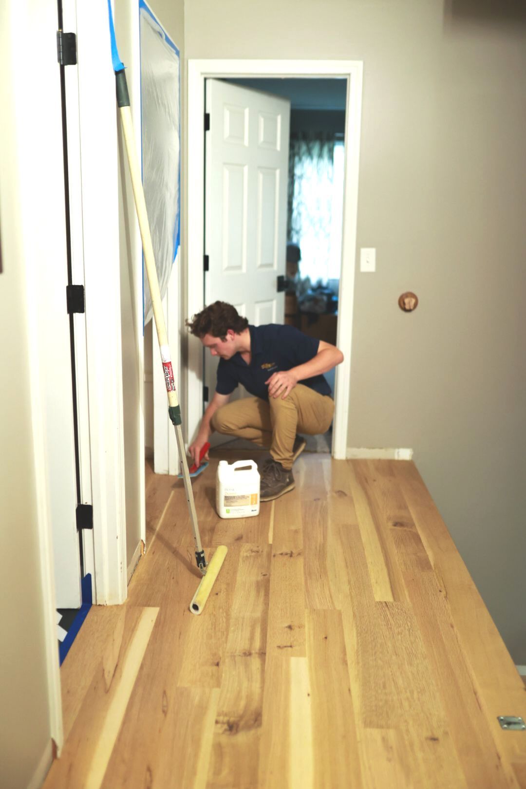 Owen is kneeling down on a wooden floor in a hallway.