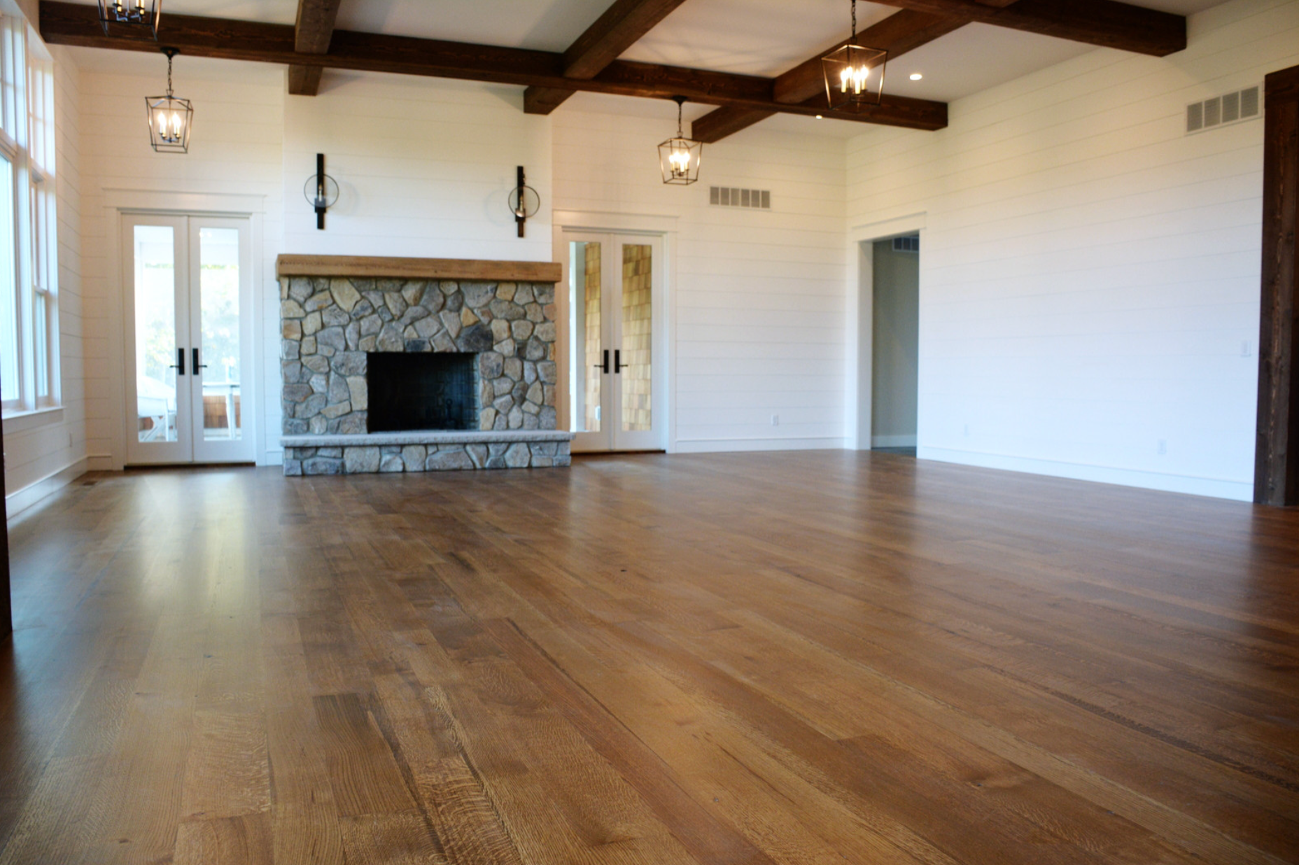 An empty living room with hardwood floors and a fireplace.