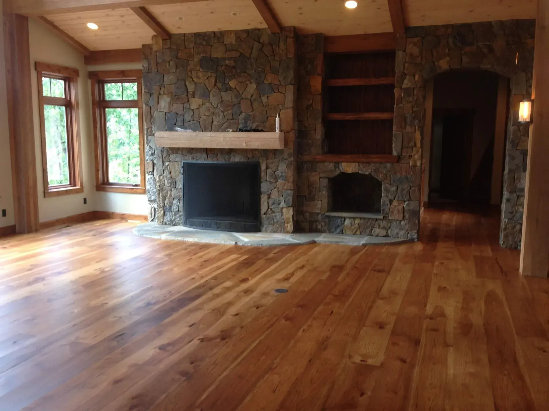 A living room with hardwood floors and a stone fireplace.