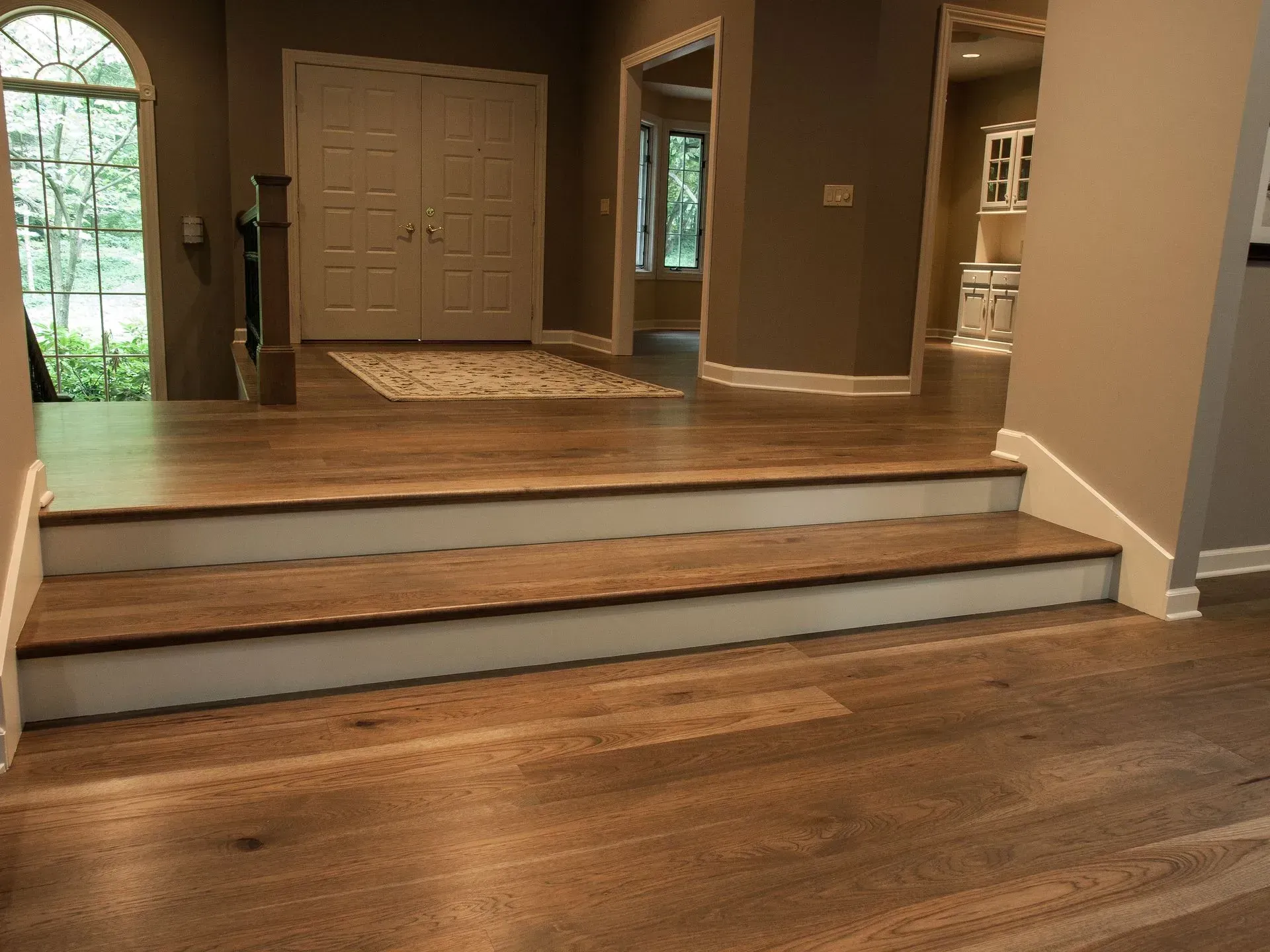 A hallway with hardwood floors and white stairs