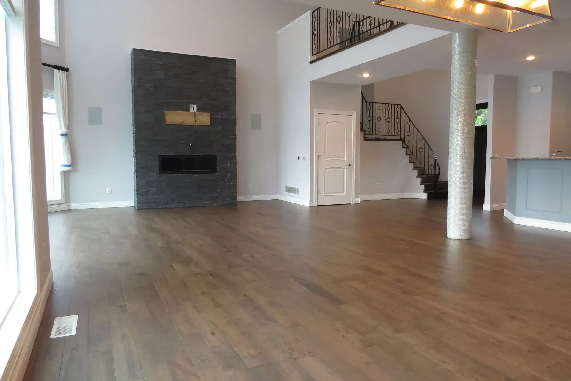 An empty living room with hardwood floors and a fireplace.