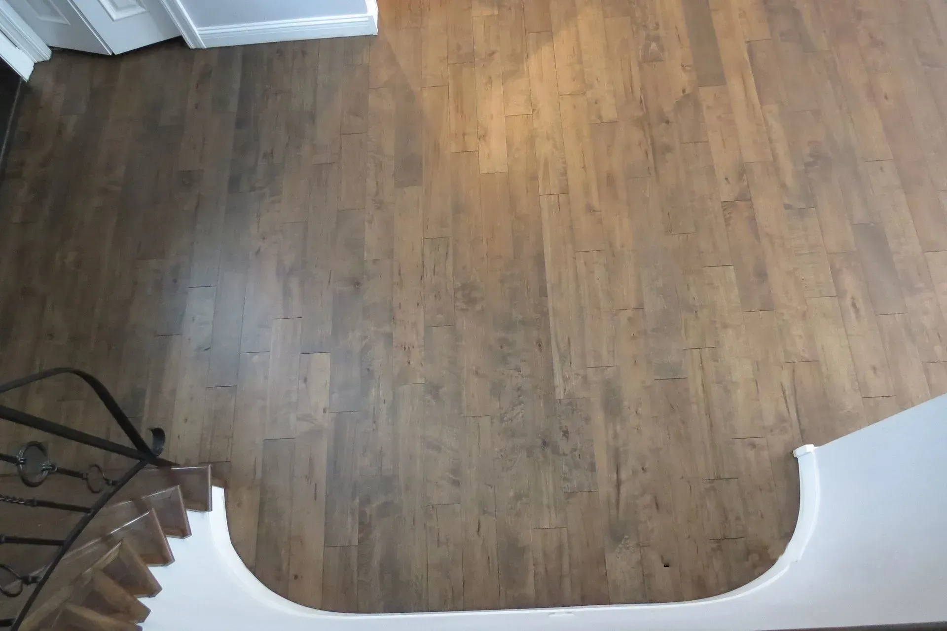 A view of a wooden floor from the top of a staircase.
