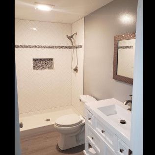 A bathroom with a toilet , sink , shower and mirror.