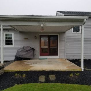 The back of a house with a covered porch and a grill.