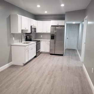 A kitchen with white cabinets , stainless steel appliances , and hardwood floors.