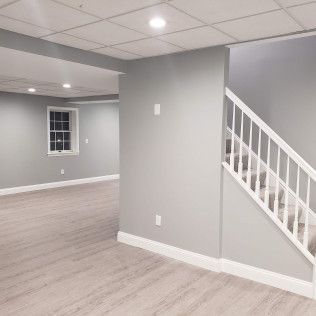 An empty basement with stairs and a window.