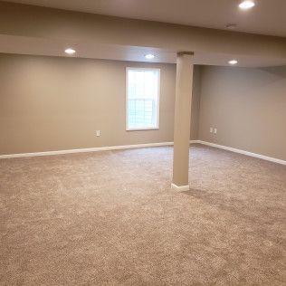 An empty basement with a pillar and a window.