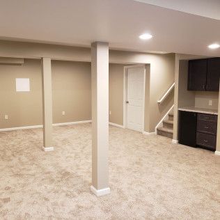 An empty basement with a staircase leading up to the second floor.