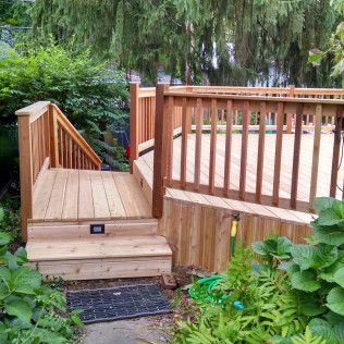 A wooden deck with stairs leading up to it in a garden.