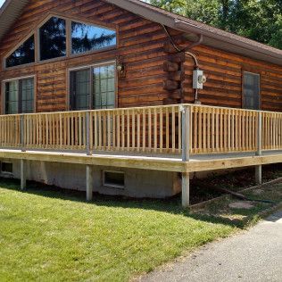 A log cabin with a wooden deck and railing.