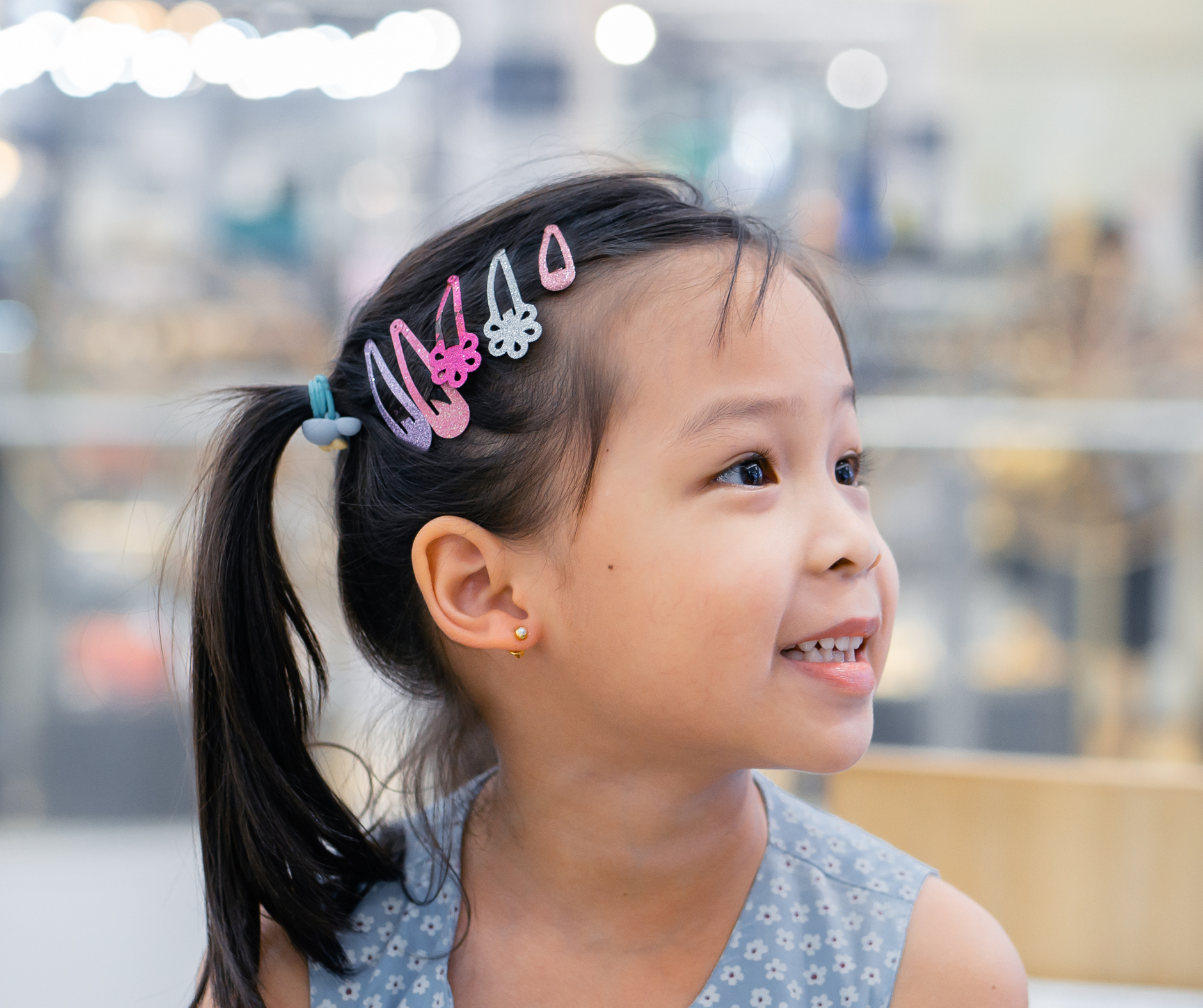 A little girl with a ponytail and hair clips in her hair.