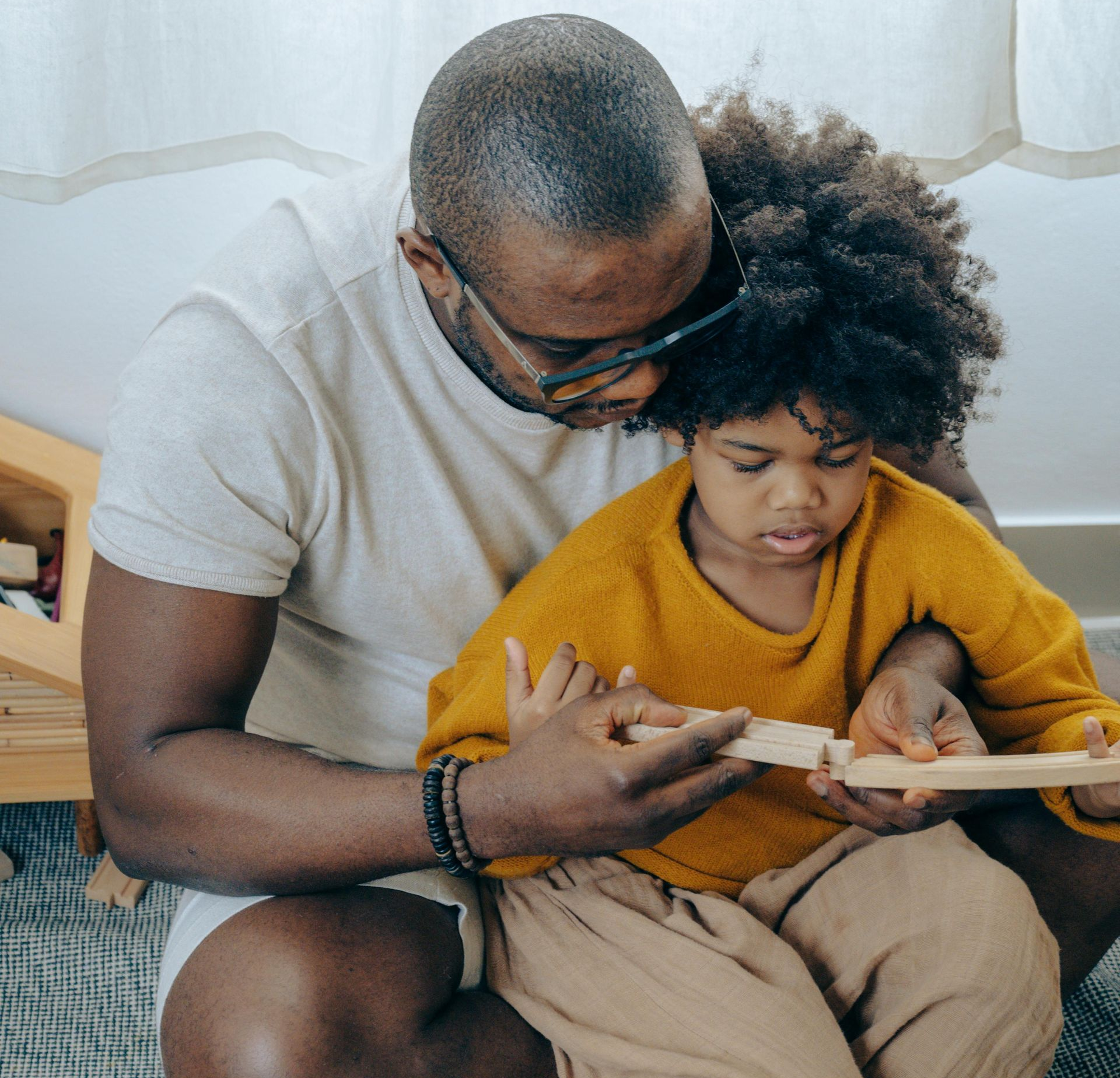 Adult and child reading a book together on a couch, with the adult pointing to the page