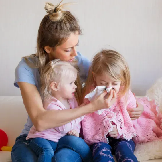 A woman is sitting on a couch with two little girls.