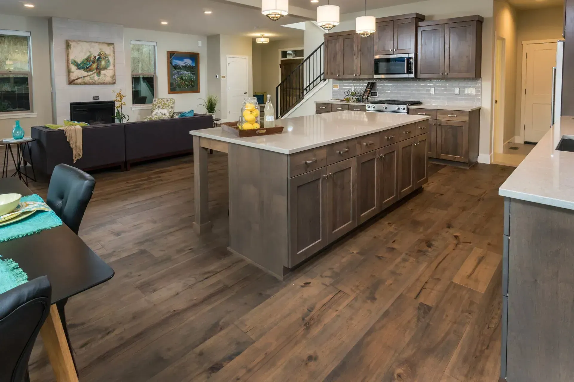 Modern open-concept kitchen and living room with dark wood floors, gray cabinets, and a large island