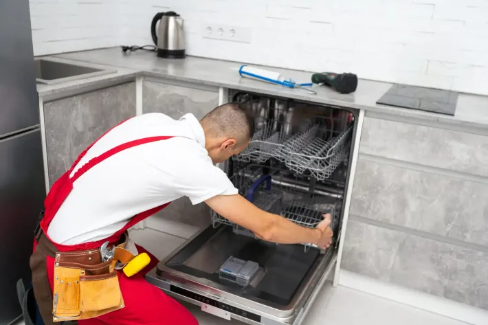 Technician loading a built-in dishwasher in a modern kitchen