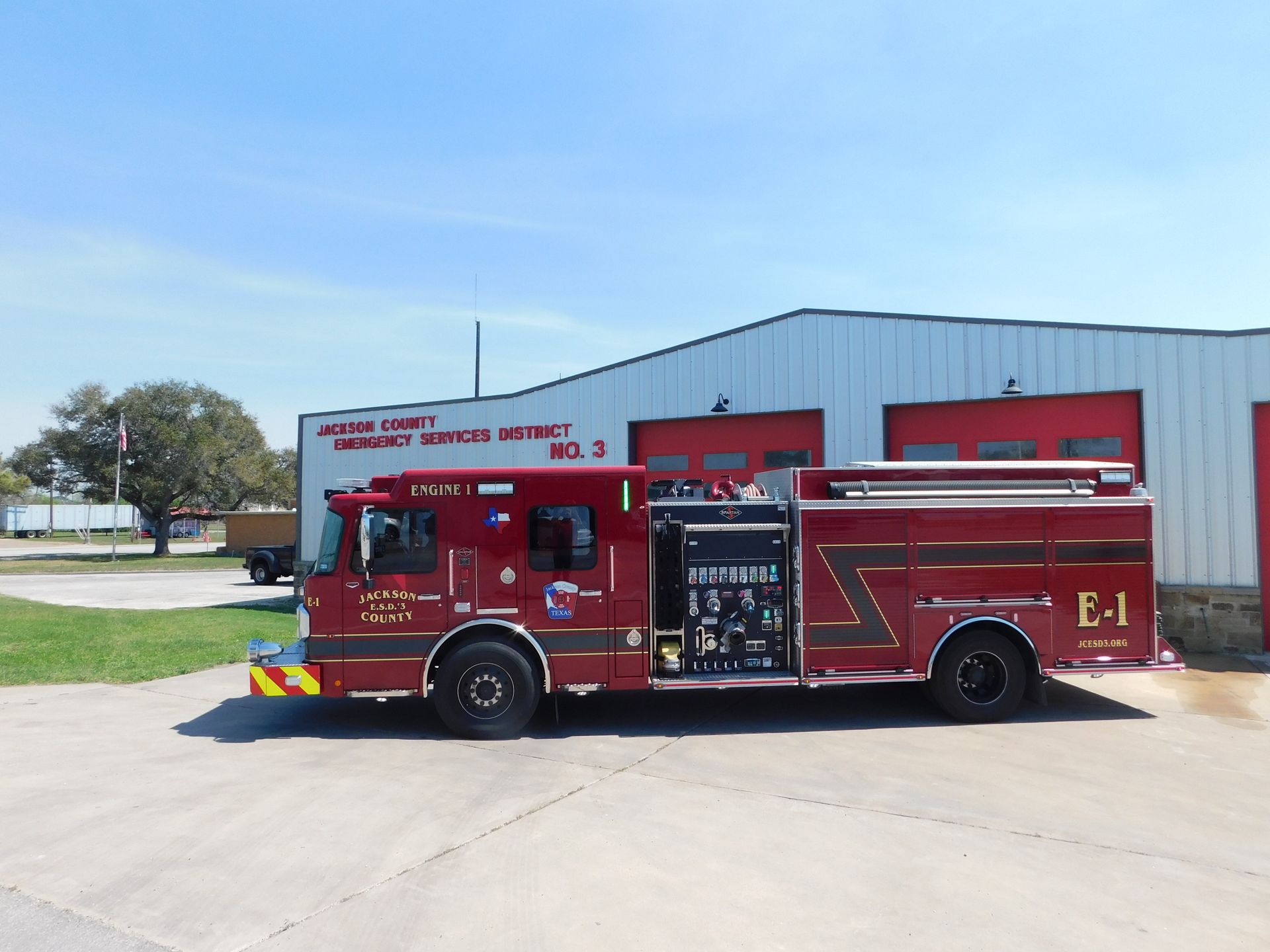A red and white Jackson Fire County fire engine parked on a concrete lot under a blue sky.