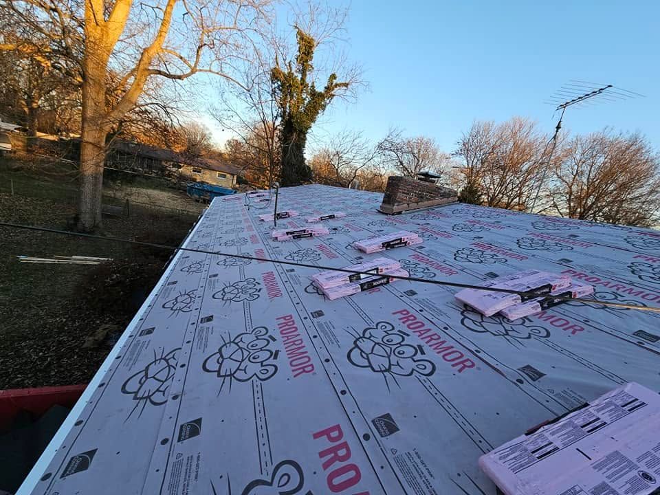 Roof underlayment on a sloped roof with trees and sunset sky in the background