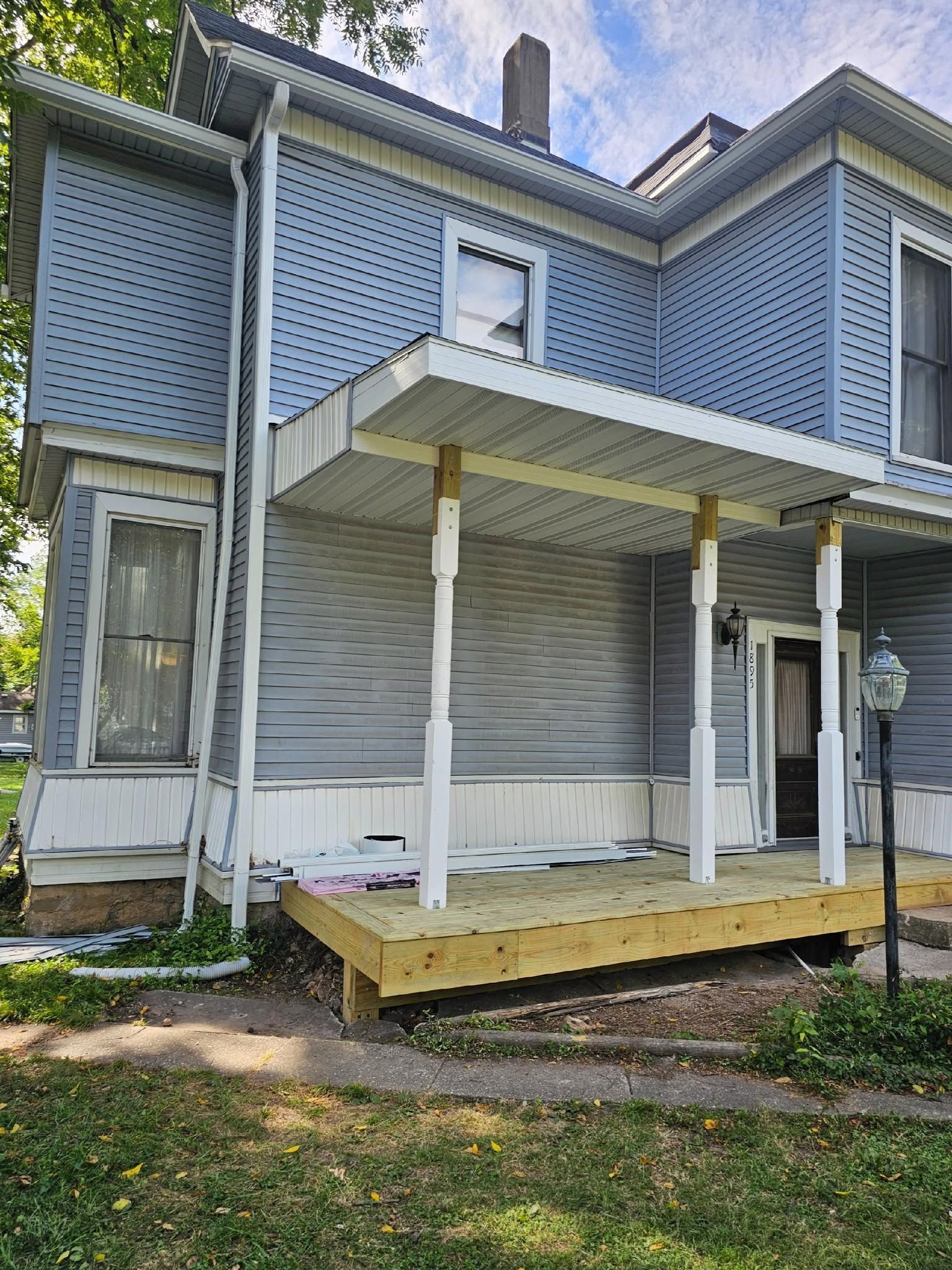 Side view of a house with a small covered porch, white posts, and blue lattice siding