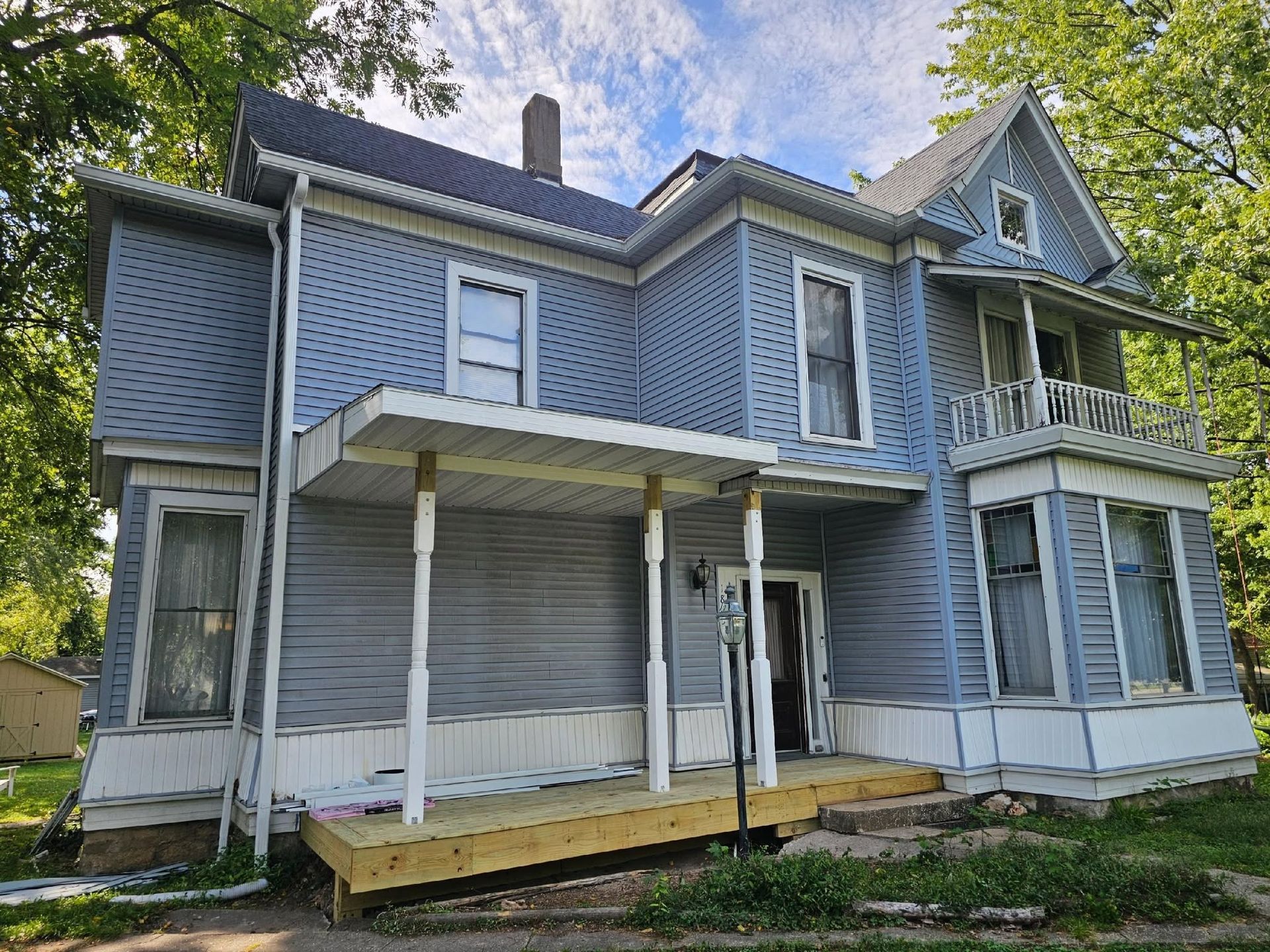 Blue two-story house with a covered front porch and white trim, seen from the frontyard