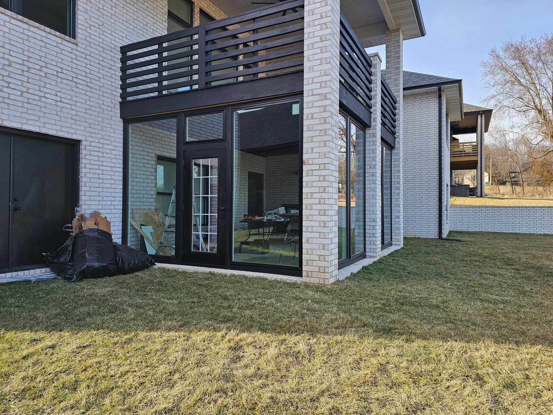 Modern brick townhouse patio with black balcony and glass doors opening onto a grassy yard