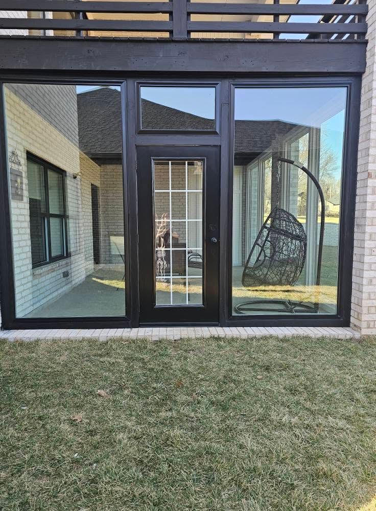 Patio with black-framed glass doors, a hanging chair, and a grassy backyard under a balcony.