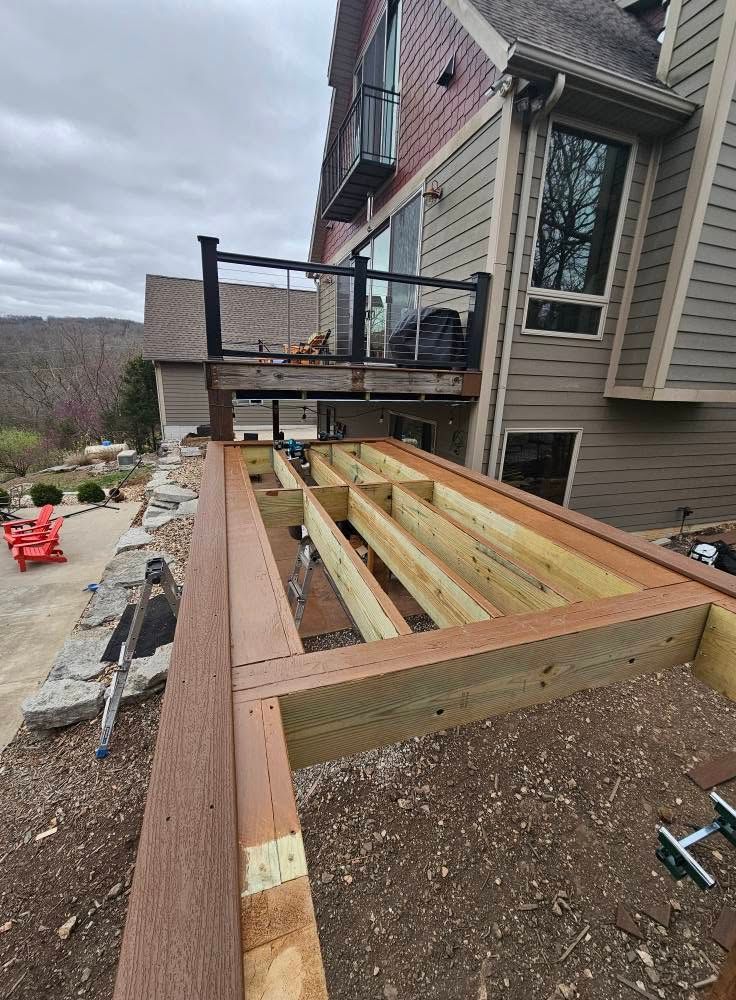 Partially built wooden deck beside a house with railing posts and framing under construction