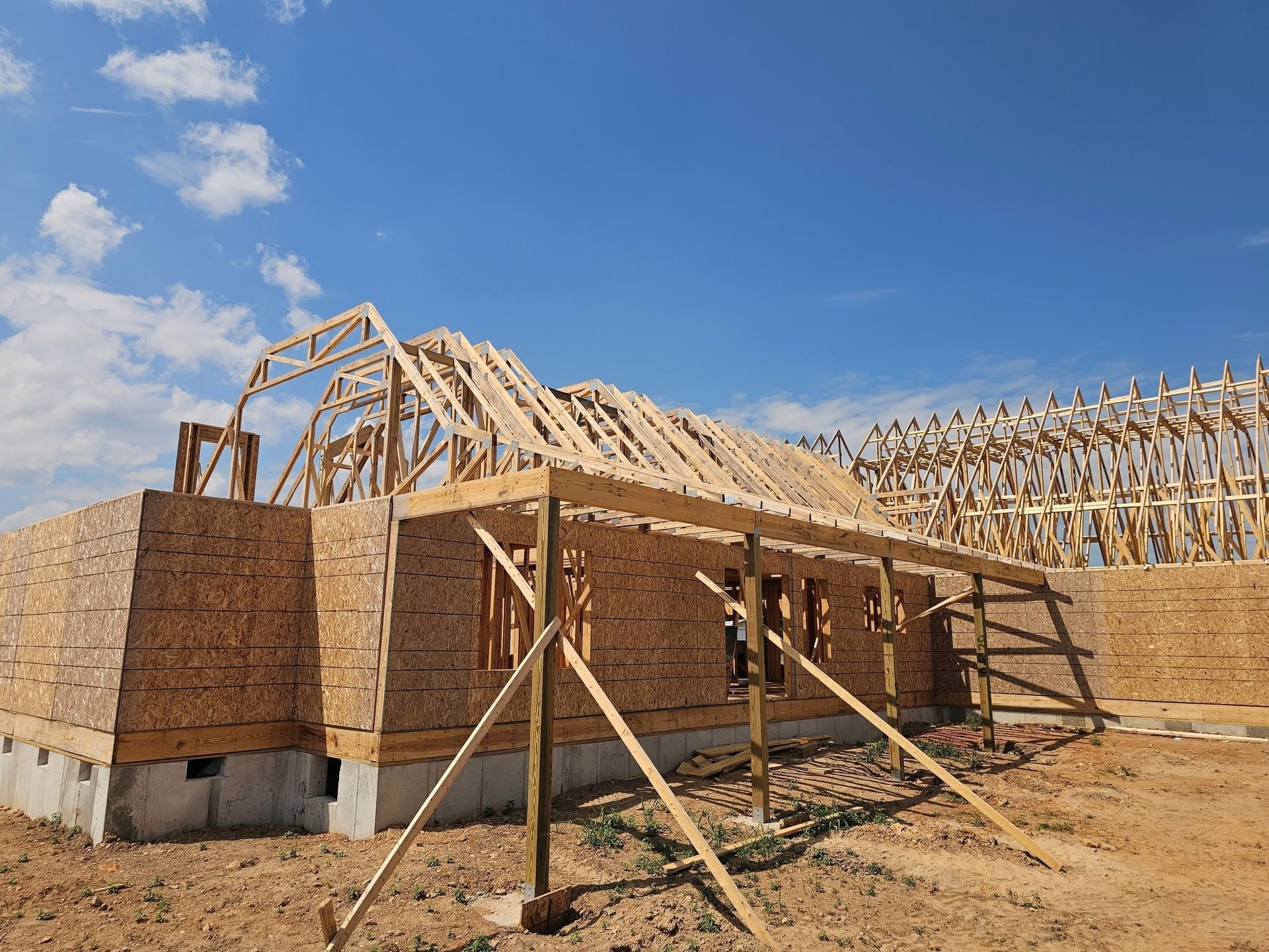 Wood-framed house under construction with exterior sheathing and blue sky above