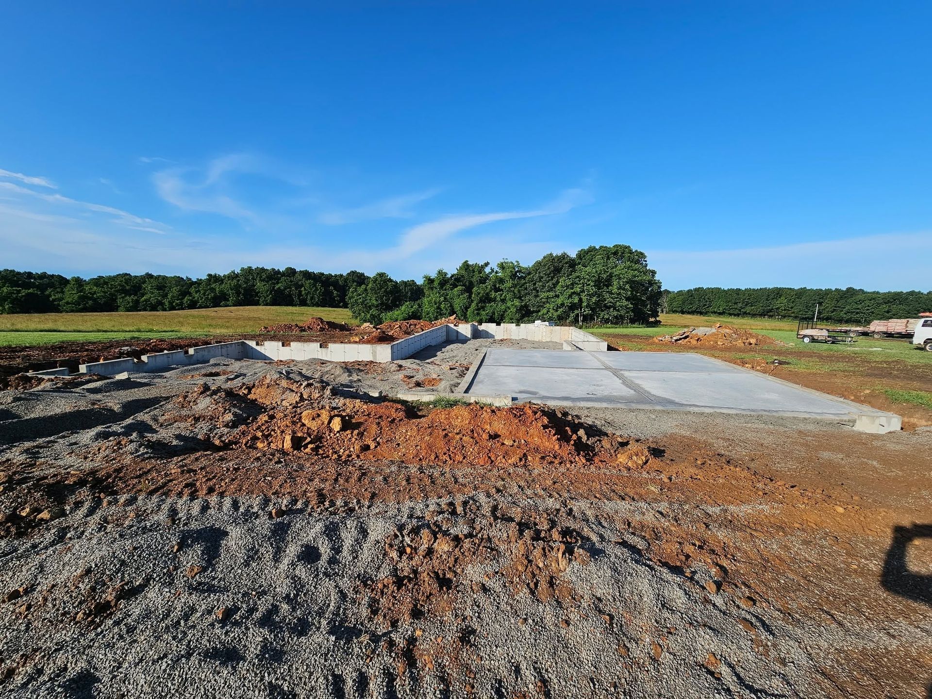 Construction site with gravel piles and a concrete slab under a clear blue sky