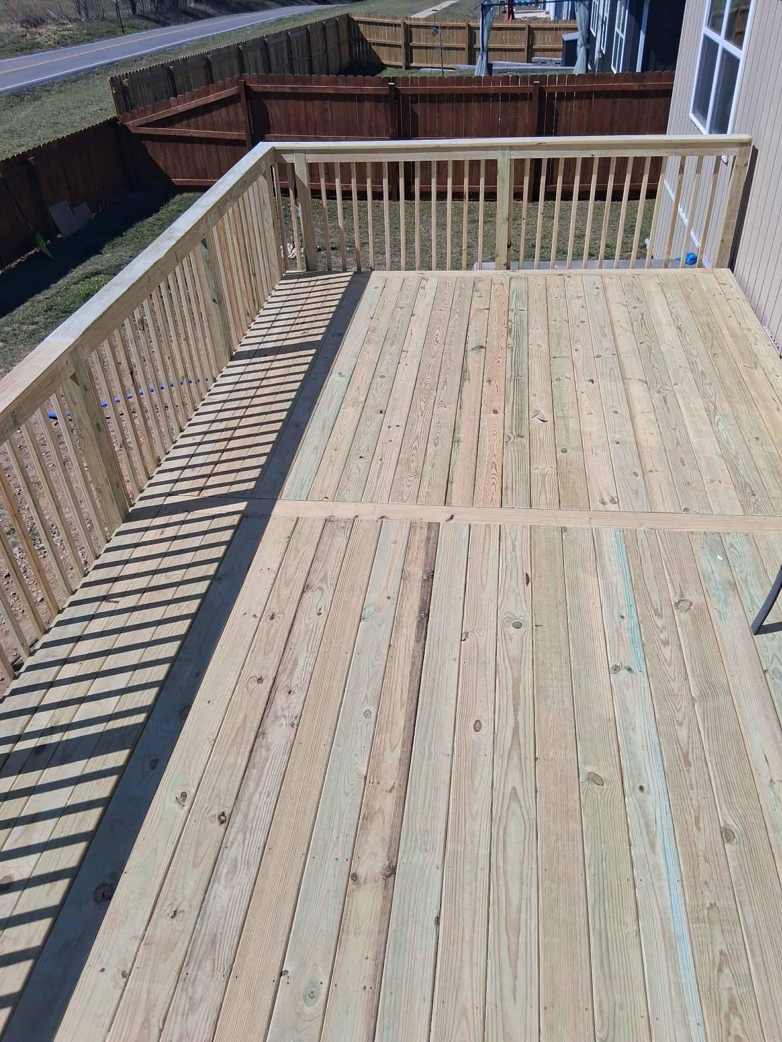 Wooden deck with railing overlooking neighboring yards on a sunny day