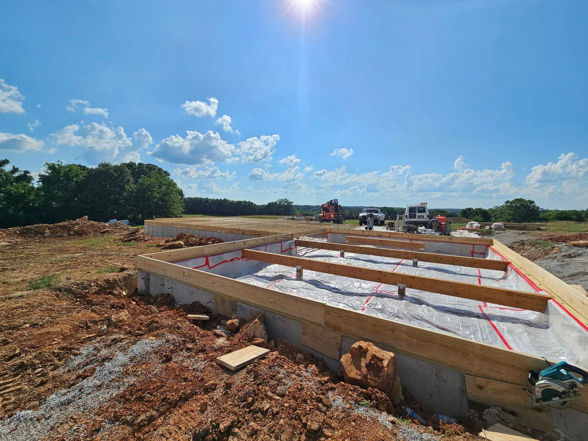 Concrete foundation under construction in a cleared field on a sunny day