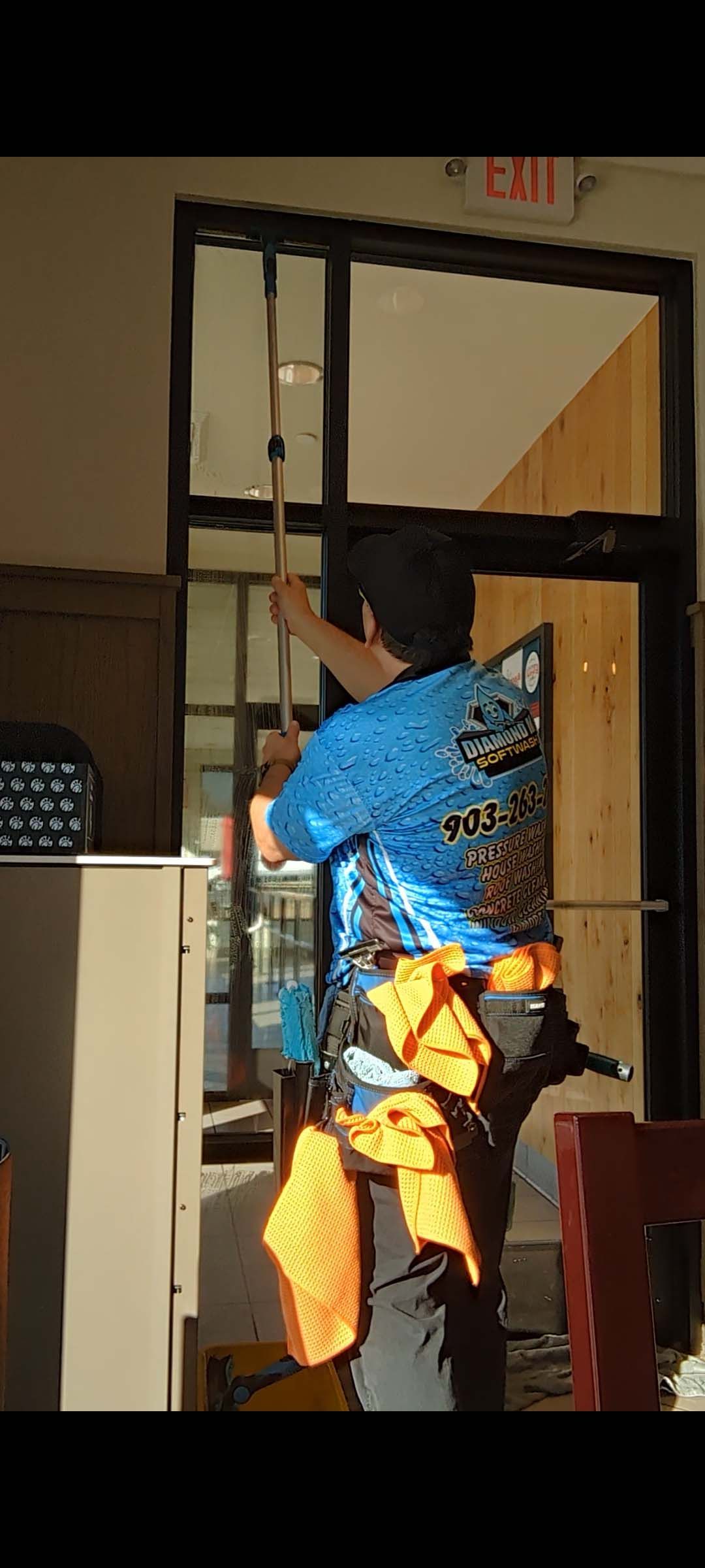 Person in a blue shirt reaching up to adjust something on a hanging window blind indoors.