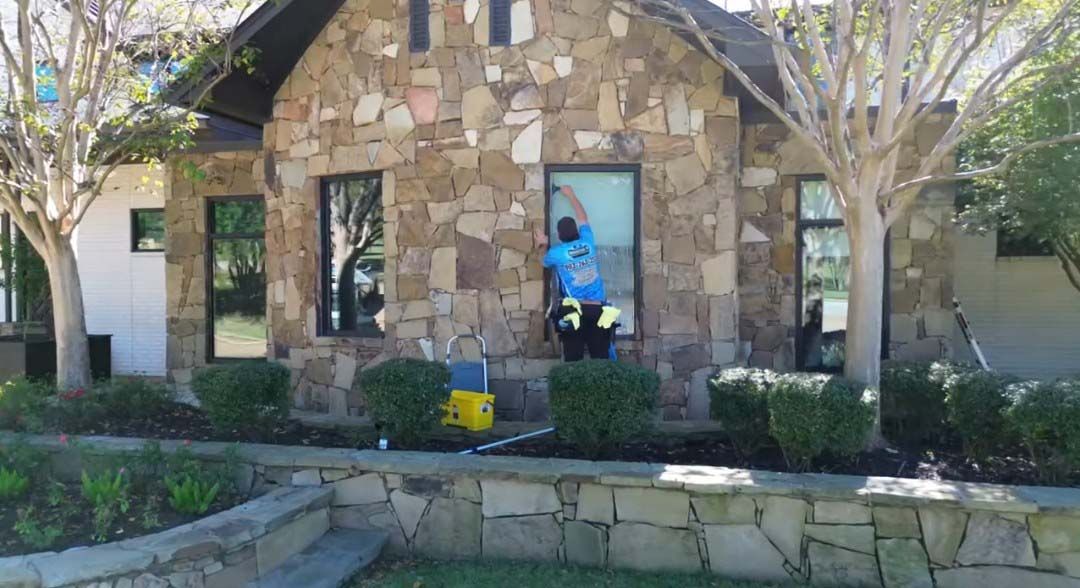 Stone house exterior with a person in a blue shirt standing in the doorway amid a front garden