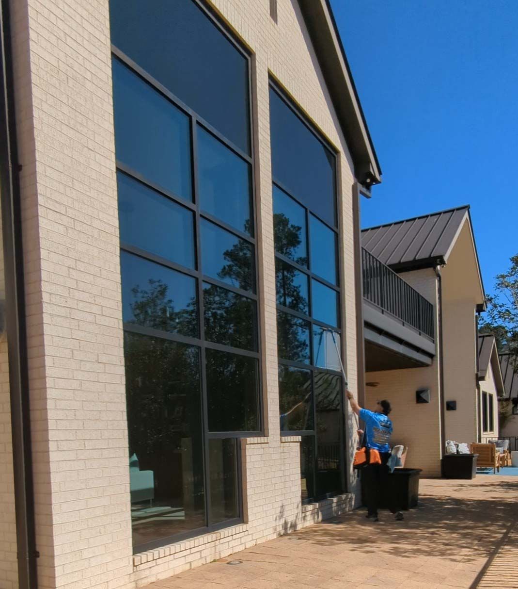 Modern apartment buildings with reflective windows on a sunny day; a person in blue stands near trash bins.