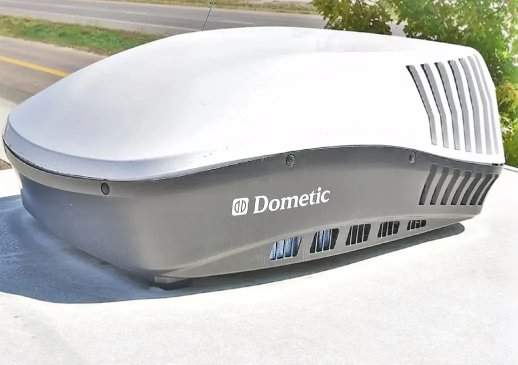 Dometic RV air conditioner unit on a white roof, gray and white with vents.