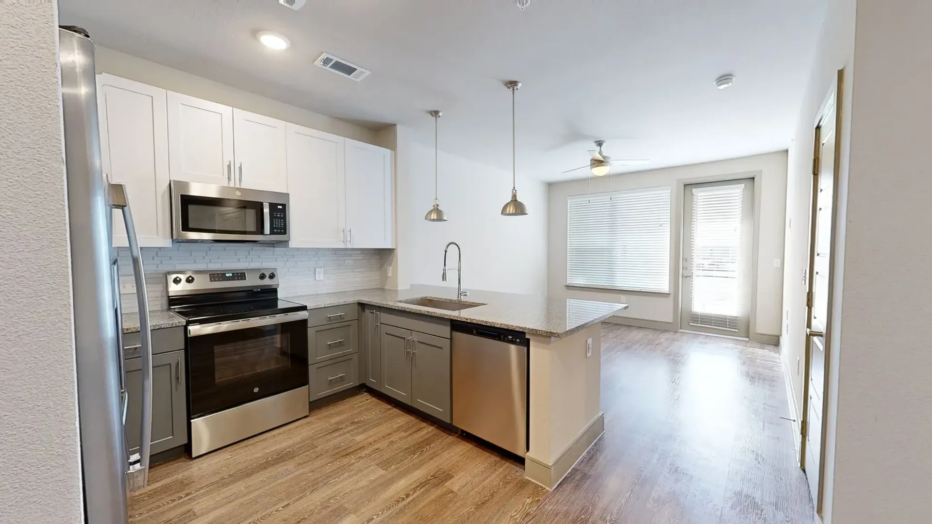 Open-concept kitchen with stainless steel appliances, island, and granite countertops.