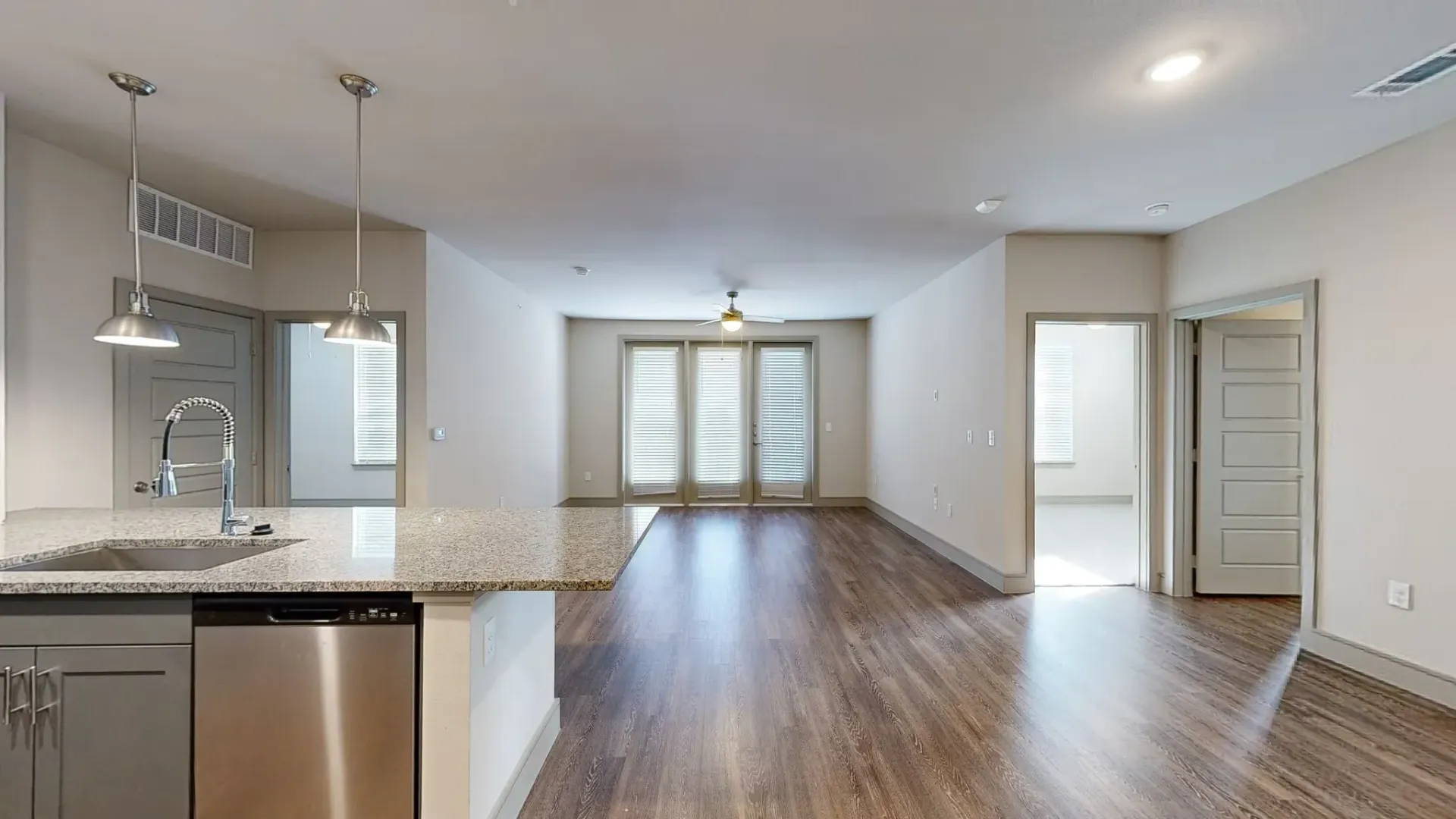 Open-concept kitchen with island, sink, and dishwasher overlooking the living area.