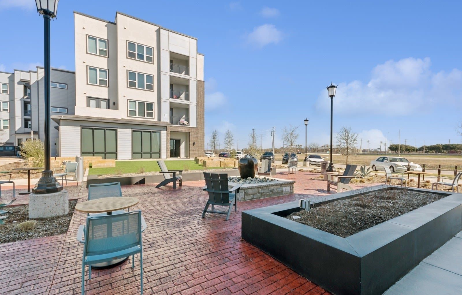 Exterior community courtyard with seating, a fire pit, and a modern apartment building in the background.