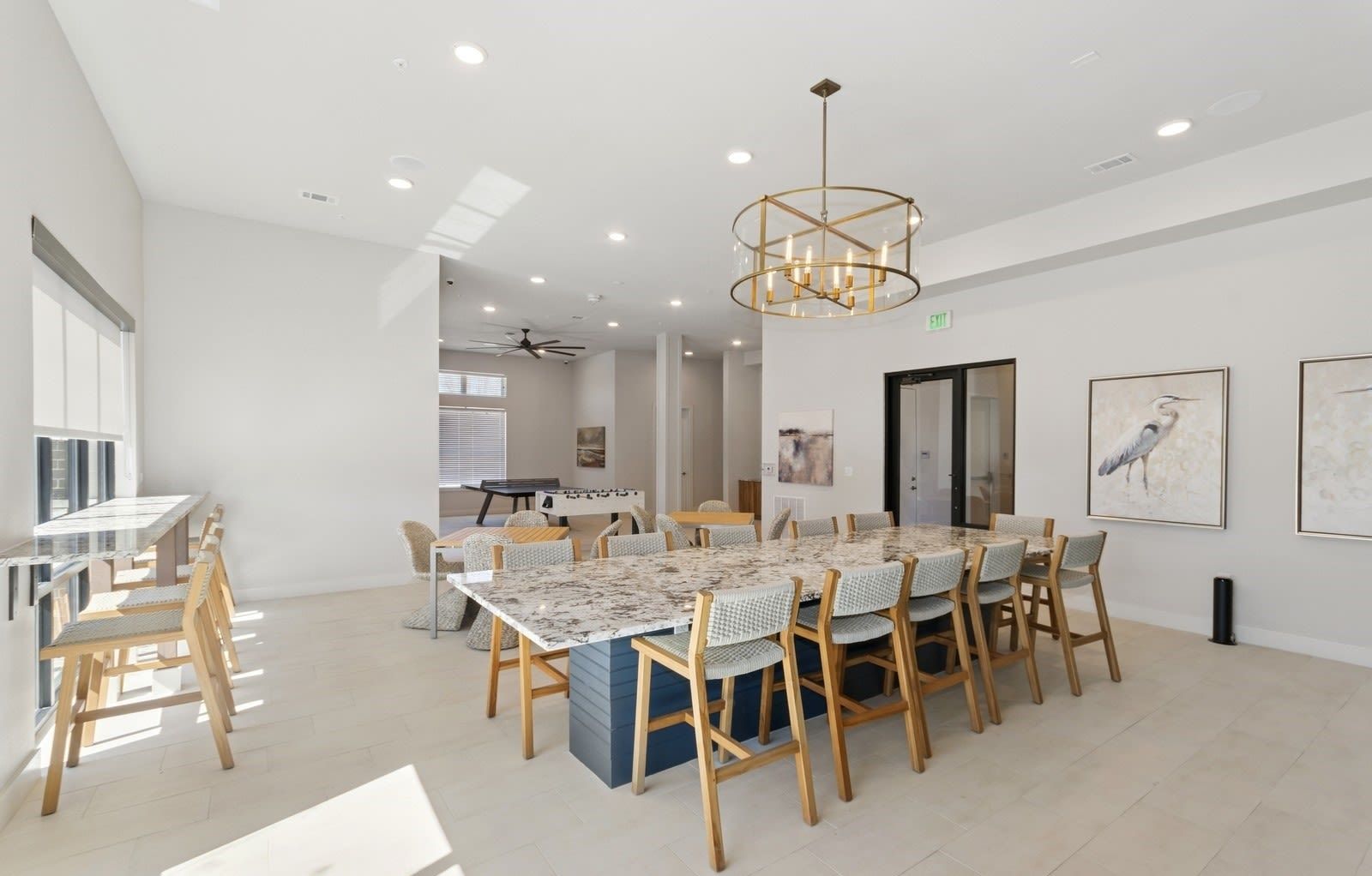 Bright community lounge with a large marble-top table, chairs, and wall art.