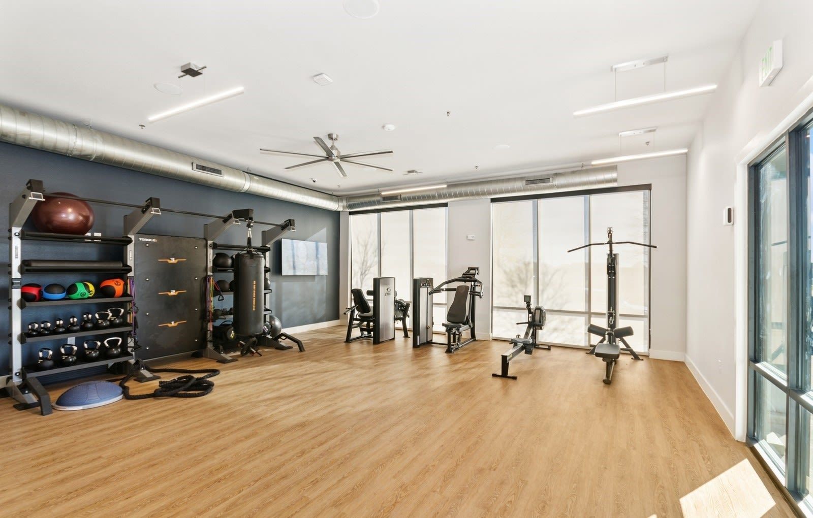 Well-lit community gym with cardio machines and free weights.