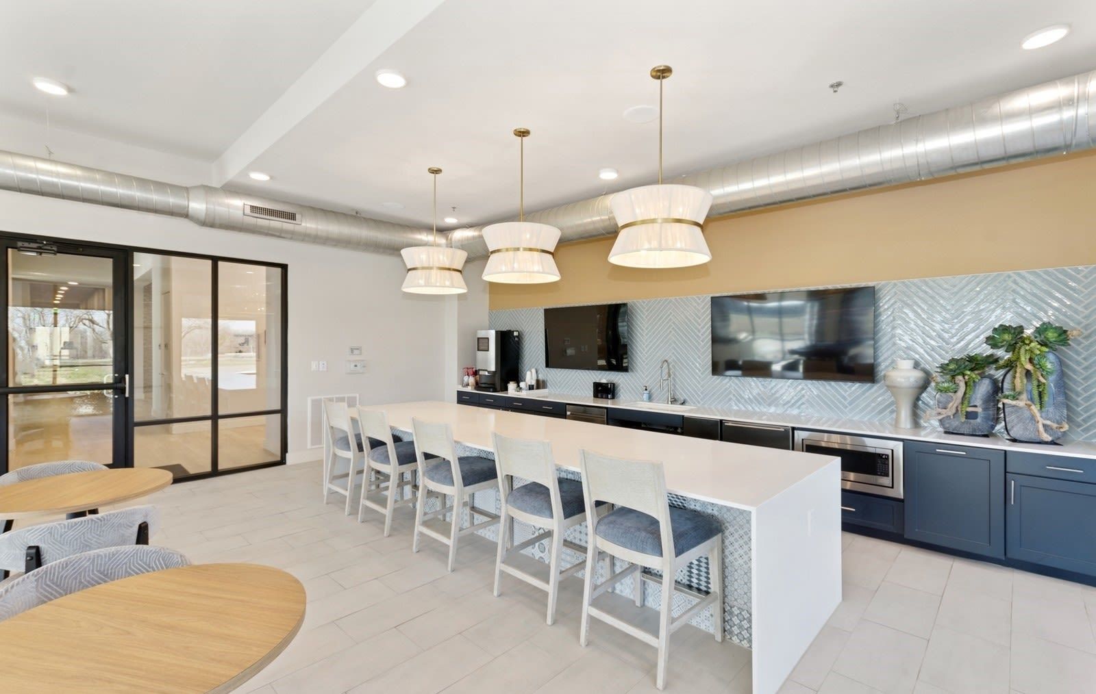 Modern community kitchen with long island, bar stools, and a mounted TV.