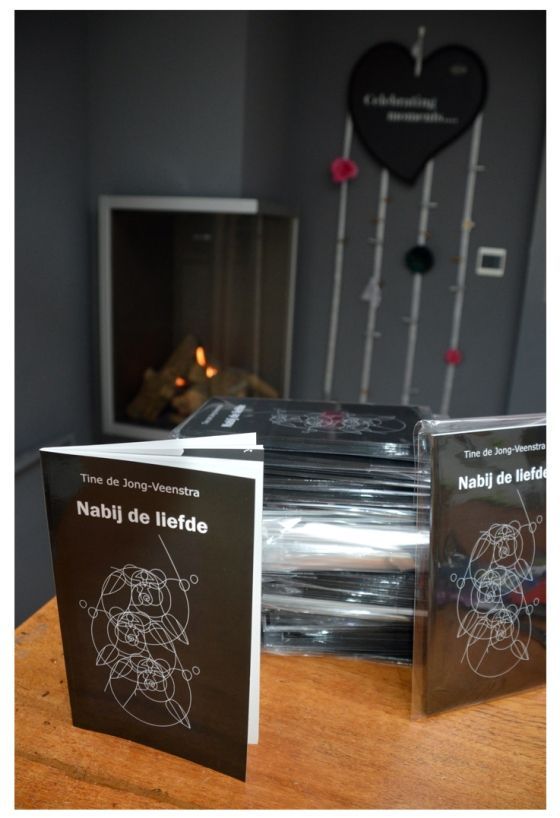 Een tafel met een stapel boeken, waaronder een zwart boek met de titel 