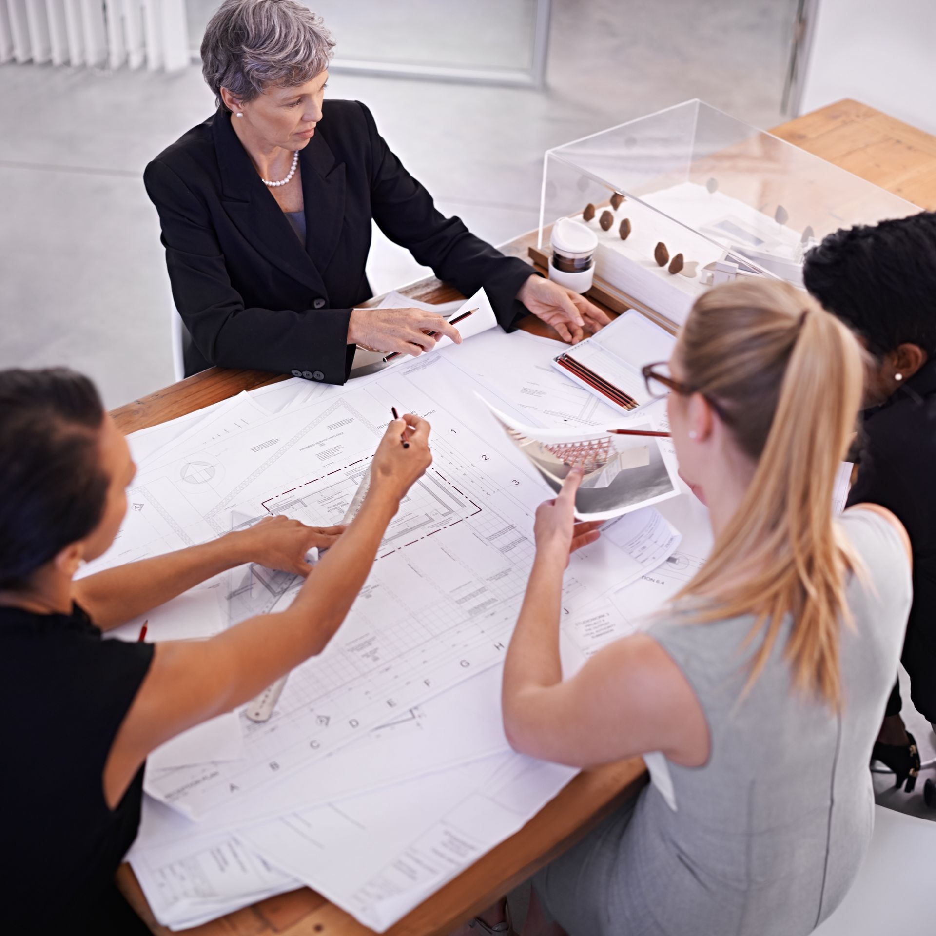 A group of people are sitting around a table looking at blueprints
