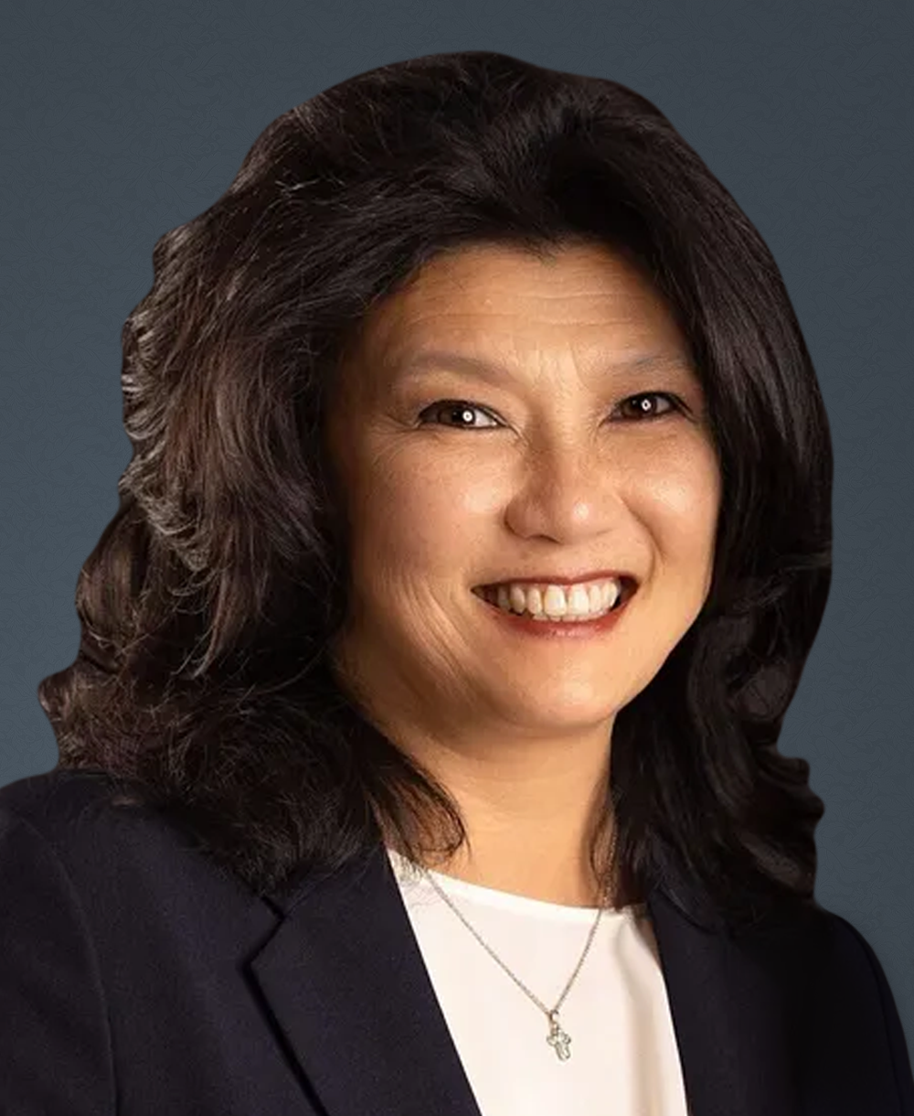 A woman in a blue jacket and white shirt is smiling for the camera.