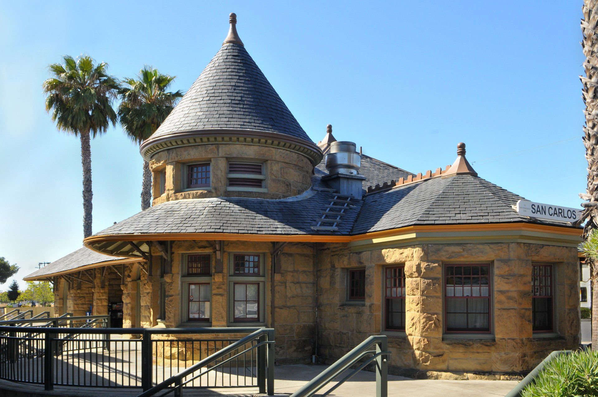 A large brick building with a conical roof and palm trees in the background